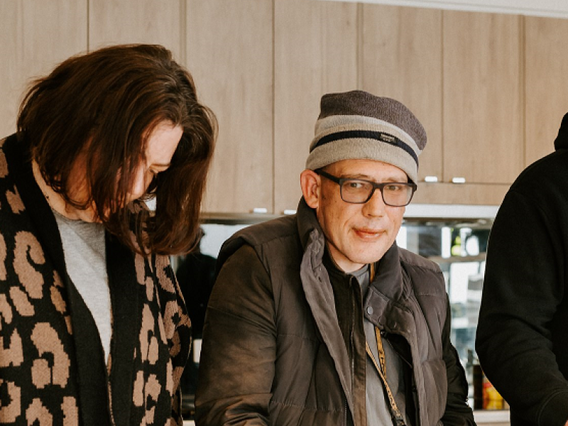 Two people working at a kitchen bench making a meal
