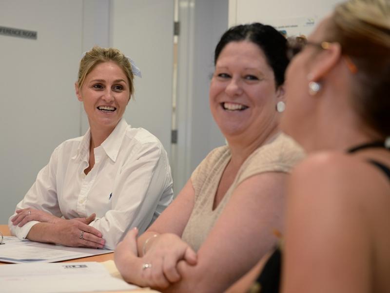 Three women at a table smiling