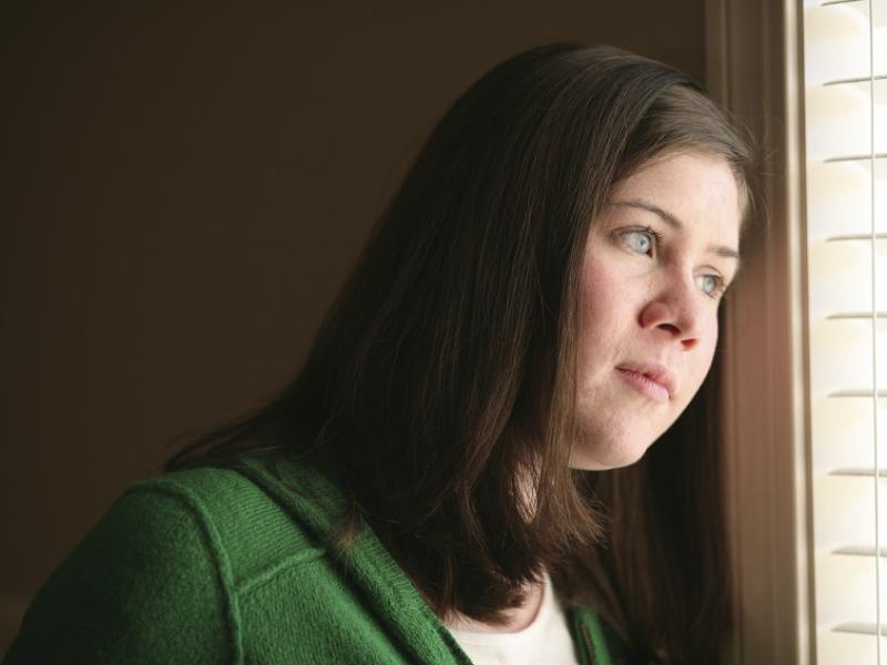 Woman sadly looking out a window