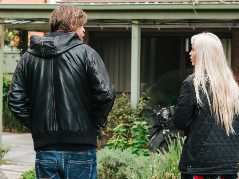A man and woman walking through a front garden with backs to the camera