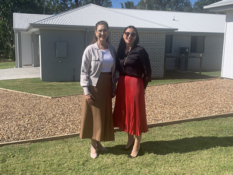 Two women standing outside a house