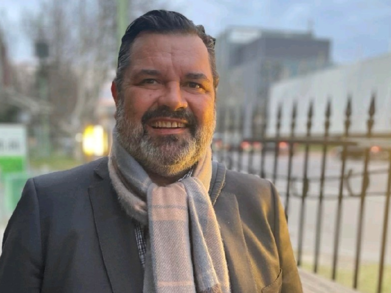 Wayne McEwan smiling with a scarf and jacket on