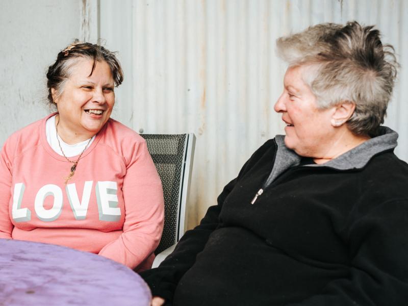 two women sitting at a table chatting.